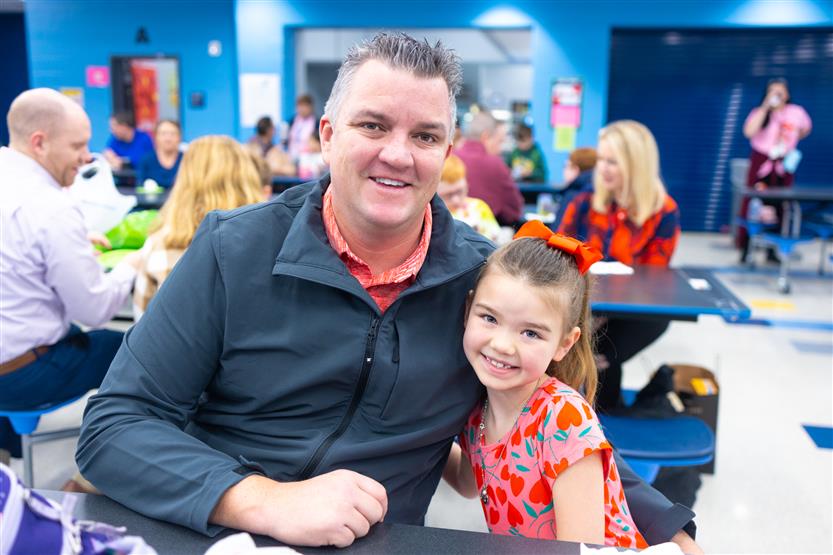 Creekside Elementary students eat donuts with a grown-up